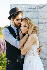 Bearded man in hat hugs tender long-haired blonde woman