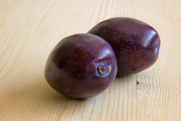 Two Plums Isolated on Wooden Background