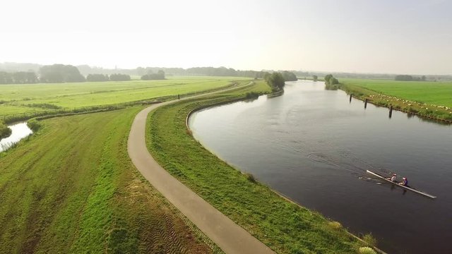 Canoe on typical dutch river. On the dikes are sheep and there is a walker.