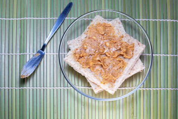 A macro  of peanut butter being spread on whole wheat bread