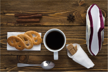 Cup of coffee on a wooden table, sugar, spoon, biscuits, napkins, top view