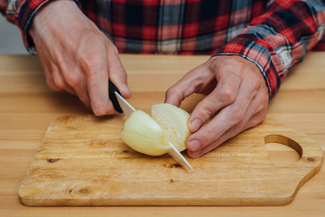 Man hands slicing fresh onnion by ceramic knife