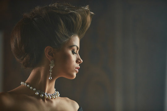 Long pearl earring hangs from an ear of beautiful model with hig