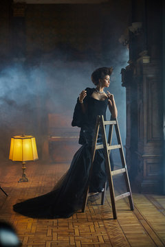 Model stands on the step-ladder in the room full of smoke