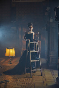 Graceful model stands on a wooden step-ladder in old room