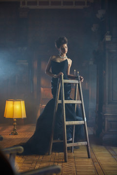 Lady dressed for a party poses on a wooden ladder
