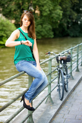 young woman sitting on railing and looking at watch