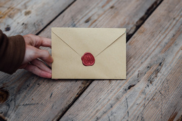 Man hand with wax seal envelope on wooden background