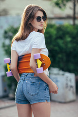 Sport fashion brunette girl in denim shorts, posing in summer wi