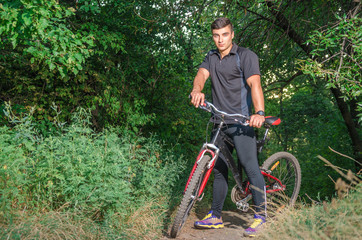 Mountainbiker riding on bicycle in summer park at sunny day.