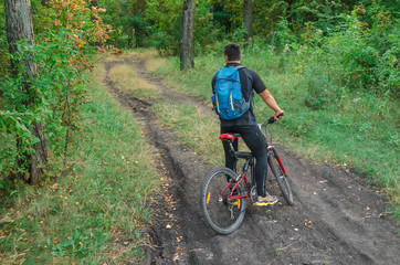 Mountainbiker riding on bicycle in summer park at sunny day.