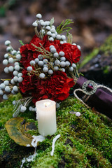 Red wedding bouquet stands on the stone covered with moss