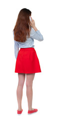 back view of a woman talking on the phone.  backside view of person.  Rear view people collection. Isolated over white background. Long-haired brunette in red skirt and white talking on a smartphone.
