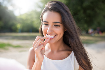 Amazing and beautiful close-up portrait of young happy woman, smile and eat cotton candy on nature background. Inspiration