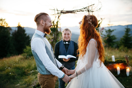 Red haired bride and groom laugh during the wedding ceremony