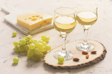 Two glasses of white wine with grapes, cheese and nuts