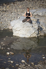 Amazing beautiful girl does yoga near the river.