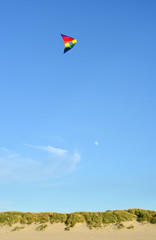 Sanddunes in france and a colorful kite flying in the sky
