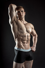 Fototapeta na wymiar Muscular bodybuilder guy doing posing over black background