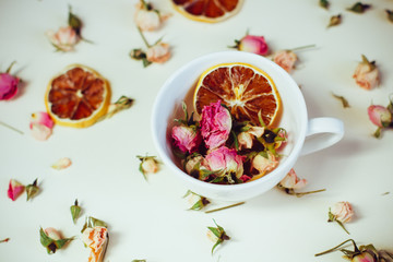 dried flowers dried roses and round slices of lemon laid on a white background and the white Cup