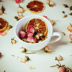 dried flowers dried roses and round slices of lemon laid on a white background and the white Cup