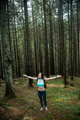 Young beautiful girl tourist with a Hiking backpack and a sports figure walking in the woods