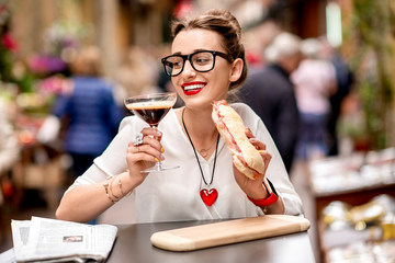 Shakerato drink in cocktail glass with panini and newspaper on the table. Italian lunch with traditional coffee and sandwich with prosciutto