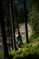 Naklejka na ściany i meble Young beautiful girl tourist with a sports figure walking in the woods