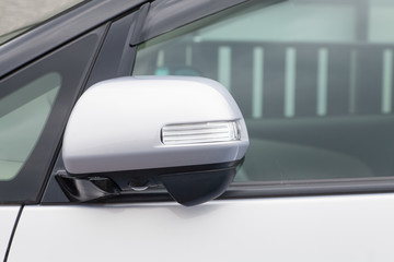 Side rear-view mirror closed for safety at car park.