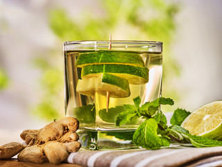 Healthy detox drink with ginger . On wooden boards short glass with green tea and mint. A mint...