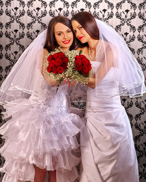 Wedding lesbians girl in bridal dress. Happy lesbians newlyweds keeps roses bouquet.