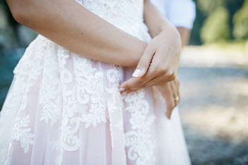 Bride corsses her tender hands on her lace skirt