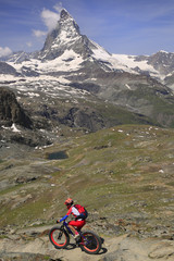 Fototapeta na wymiar View of Matterhorn and cyclist enjoying the challenge on mountain trails.
