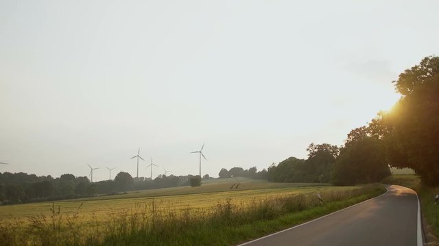 Modern wind turbines generating sustainable energy in a field with road