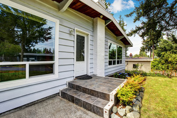 Front entry door of American siding house with tile floor porch.