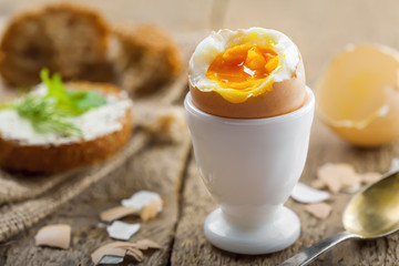 Perfect soft boiled egg and open bread sandwich with butter and dill on a table. Traditional food for healthy breakfast.