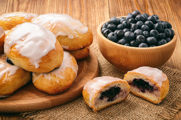 Sweet yeast buns with blueberries  on brown wooden table. 