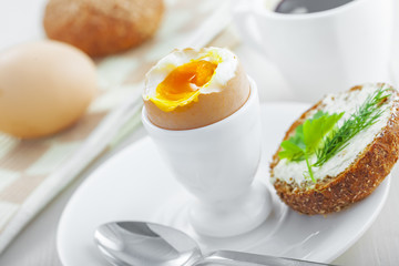 Perfect soft boiled egg, bread and butter, cup of coffee for delicious healthy breakfast on a table. Traditional homemade food.