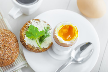 Healthy breakfast with perfect soft boiled egg, bread and butter, coffee cup. Delicious homemade food.