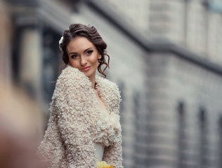 Enchanting woman leans her cheek to beige coat while posing outs