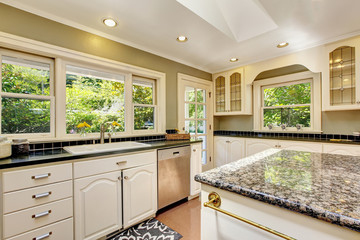 White kitchen with granite tops. Kitchen island and tile floor.