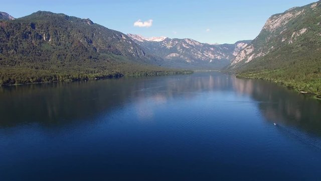 4K. Flight above amazing Bohinj Lake in the morning. People are training in rowing. Blue deep water and Julian Alps mountains. Triglav National Park, Slovenia, Europe.
