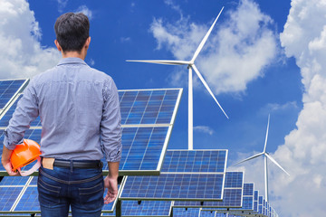        engineer stand holding yellow  helmet  in solar farm and wind turbines generating electricity power station