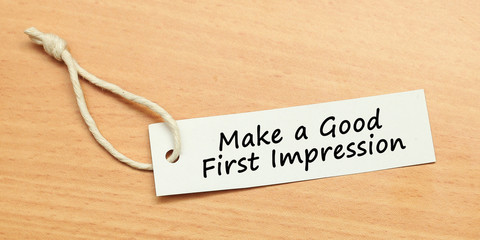White tag on wooden background with word quotes of Make a Good First Impression