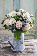 Bouquet of pink roses and white gerbera flowers in grey watering