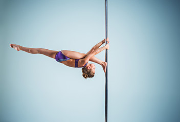 The strong and graceful young girl performing acrobatic exercises on pylon