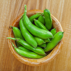 Bowl of fresh podded broad beans on a wooden table. Healthy organic food.