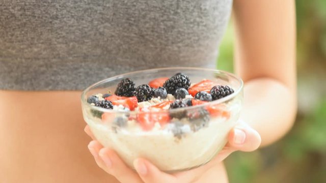 Young girl eating a oatmeal with berries after a workout . Fitness and healthy lifestyle concept.