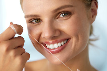 Dental Health. Woman With Beautiful Smile Flossing Healthy Teeth. High Resolution Image