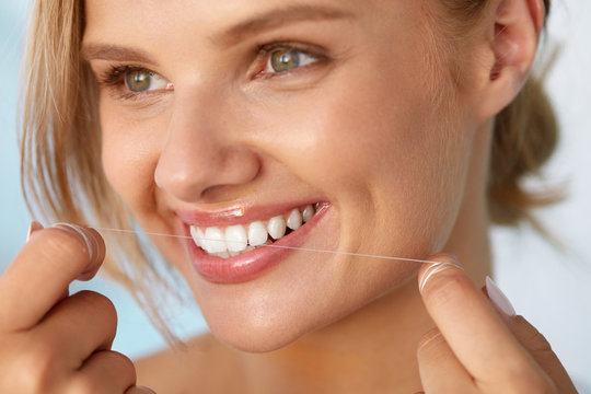 Dental Health. Woman With Beautiful Smile Flossing Healthy Teeth. High Resolution Image